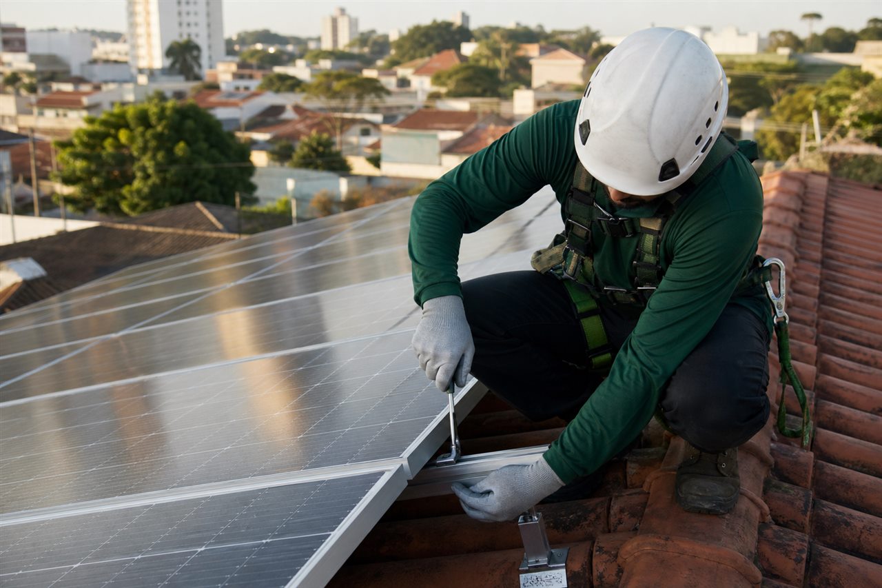 Técnico realizando manutenção em painéis solares sobre um telhado residencial